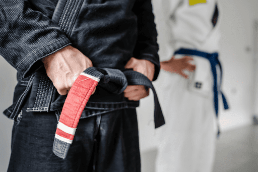 Close-up of a Brazilian Jiu-Jitsu practitioner tightening a worn black belt.