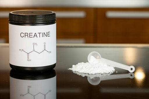 Container labeled "Creatine" with its chemical structure, next to a scoop of white powdered supplement on a reflective black surface.