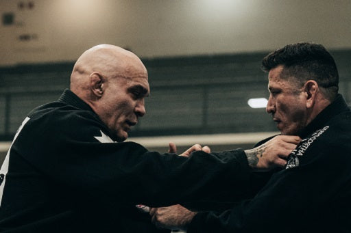 Two men in BJJ gi engage in a grappling session.