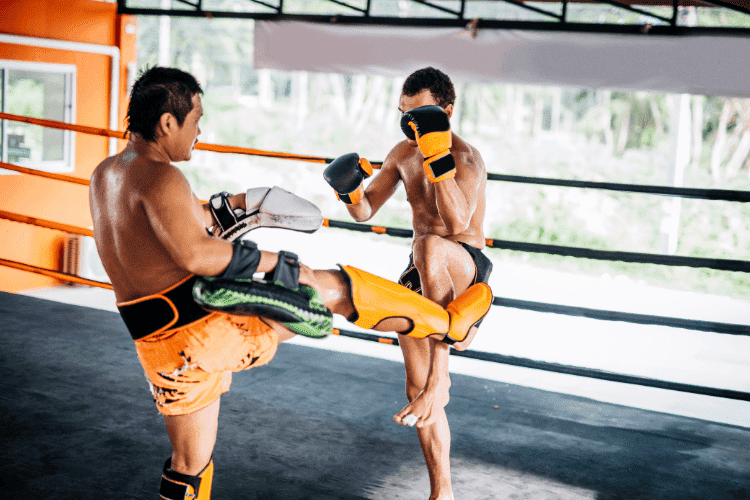 Two Muay Thai fighters sparring in a boxing ring during training.