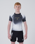 Kingz Galaxy Youth Rashguard Black White - Full Body Front View Teen Boy Athlete Short Sleeve Black White Ombre Galaxy Pattern Gold Star KINGZ Gold Text Crown Logo Black Shorts Kids BJJ