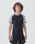 Kingz Ranked Youth S/S Rashguard Navy Gray - Full Body Front View Teen Boy Athlete Short Sleeve Navy Body Gray Raglan Sleeves White Crown Logo Chest Gray Side Stripes Matching Navy Shorts KINGZ Text Kids BJJ IBJJF Ranked