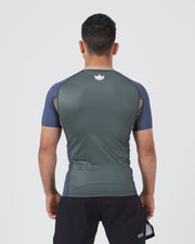 Kingz Draft Rashguard Storm Blue - Full Body Straight Back View Male Athlete Short Sleeve Crown Logo Centered Upper Back Gray Body Blue Raglan Sleeves Side Accent Stripes Black Shorts [color:Storm Blue]