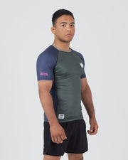 Kingz Draft Rashguard Storm Blue - Full Body Right Side Profile View Male Athlete Short Sleeve Gray Body Blue Raglan Sleeve Crown Logo Pink KINGZ Label Side Accent Stripe KINGZ Badge Shorts [color:Storm Blue]