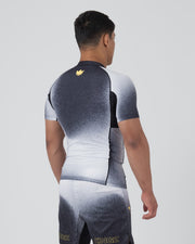 Kingz Galaxy Rash Guard Black White - Full Body 3/4 Back Left Side View Male Athlete Short Sleeve Black To White Ombre Galaxy Spatter Pattern Gold Crown Logo Upper Back Matching Galaxy Shorts KINGZ Gold Text Ankle BJJ [color:Black/Galaxy]