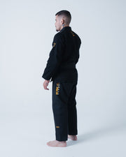 Kingz Legends Never Die Respect Gi - Black - Back View Male Athlete Black Gi Gold Crown Badge Shoulder Intricate Text Right Leg Durable Fabric BJJ Gi Training [color:Black]
