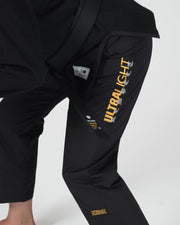 Kingz Legends Never Die Respect Women's Gi - Black - Close-Up Side View Black Pants Yellow ULTRALIGHT Vertical Text Kingz Logo Embroidered Crown Badge Durable Fabric Women's BJJ Gi Training [color:Black]