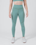 Kingz Kore Women's Grappling Spats Green - Full Body Front View Female Athlete Sage Teal Green V-Seam Front Detail Side Pocket Right Thigh High-Waist Matching Sports Bra Full-Length Compression Fit Women's No-Gi BJJ Spats Kore Collection