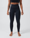 Kingz Kore Women's Grappling Spats Black - Full Body Front View Tattooed Female Athlete All-Black High-Waist Wide Waistband Small White Crown Logo Left Thigh Full-Length Compression Fit Bare Feet Women's No-Gi BJJ Spats Kore Collection